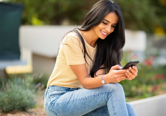 Um casal sorrindo, enquanto olha para a tela de um celular. 