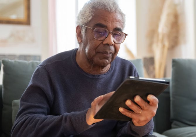 Idoso mexendo no tablet enquanto observa seu plano de aposentadoria desenvolvido com auxílio das soluções do Mercado Pago