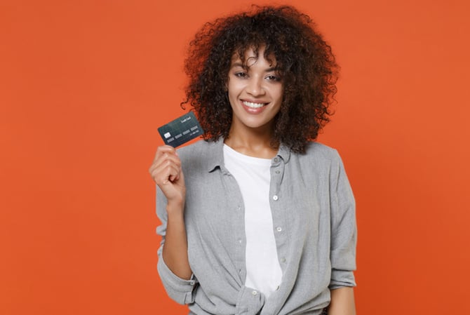 Mercado Pago: mulher sorrindo enquanto segura um cartão de crédito com limite alto na sua mão direita