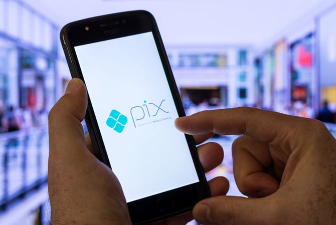 Mercado Pago: mãos mexendo em um celular em que a tela mostra o símbolo do Pix, representando que o usuário irá comprar parcelado no Pix.