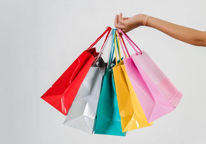 Mercado Pago: mão segurando cinco sacolas coloridas após fazer compras por impulso durante a Black Friday