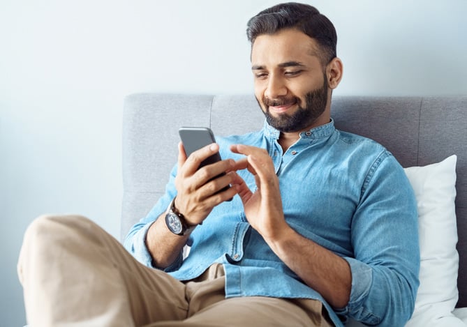 Homem sorrindo enquanto visualiza no celular a melhora do seu controle financeiro adquirido com as soluções da Conta Mercado Pago