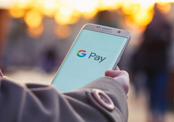 Pessoa segurando um tablet com a tela aberta no Google Pay, que agora é possível cadastrar o cartão Mercado Pago para fazer suas compras