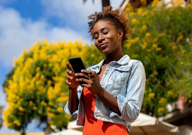 Mulher mexendo no celular enquanto acompanha quais são seus pontos e benefícios no Mercado Pontos, programa de recompensa do Mercado Pago.