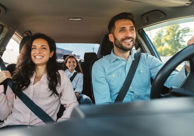 Mercado Pago: imagem de uma família formada por três pessoas, dentro de um carro, utilizando cinto de segurança. Na imagem, é possível todos sorrindo, indicando a tranquilidade por estarem utilizando uma tag de pedágio para fazerem uma viagem de carro durante as férias de julho.