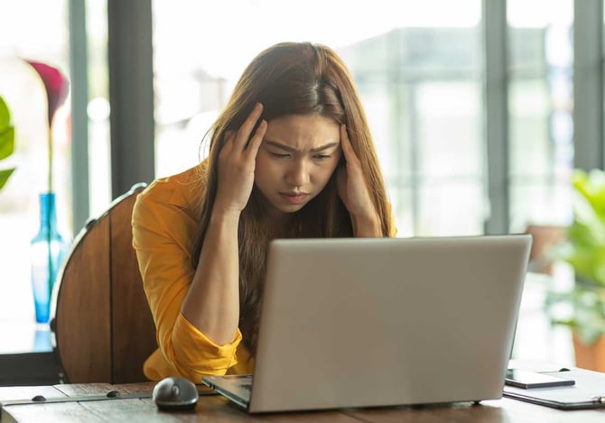 Mulher com as mães na cabeça e preocupada na frente do laptop