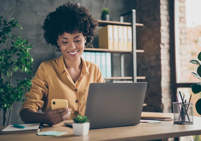 Mulher analisando seu smartphone e laptop