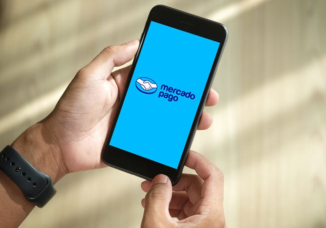 Mão segurando um celular com tela do aplicativo da Conta Mercado Pago