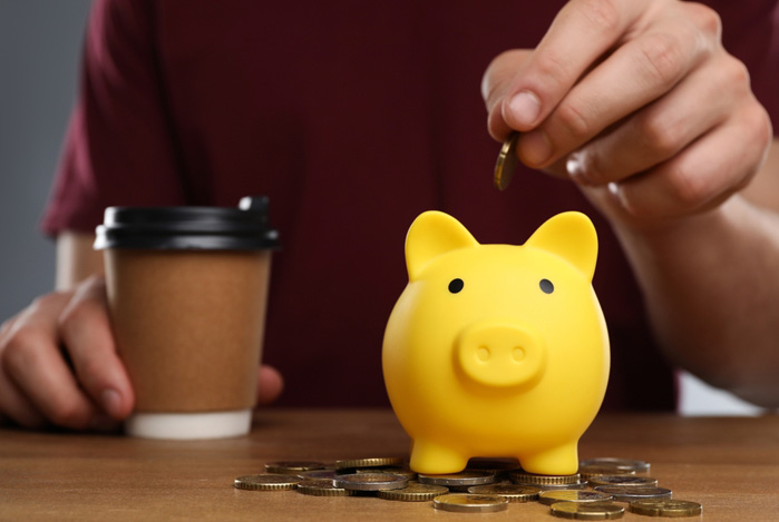 Mercado Pago: pessoa depositando uma moeda em um dos seus cofrinhos para guardar dinheiro.