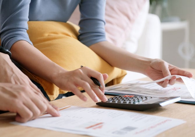 Mercado Pago: Casal analisando contas e usando calculadora para entender como fazer o dinheiro render melhor no dia a dia.