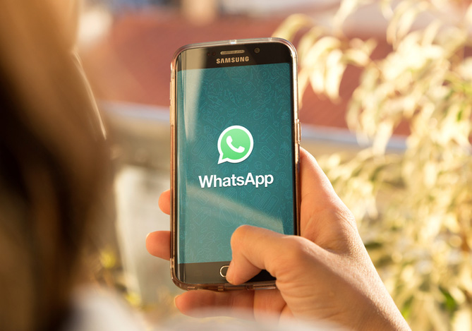 Mercado Pago: mão de uma pessoa segurando o celular enquanto ele mostra na tela o símbolo do WhatsApp. Evite o golpe no WhatsApp