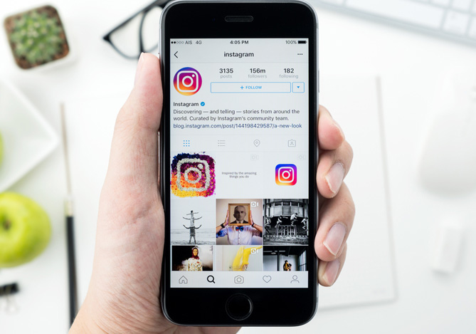 Mercado Pago: mão de uma pessoa segurando um smartphone com a tela aberta no perfil do Instagram na sua própria rede social para exemplificar formas de se proteger contra potenciais golpes no Instagram