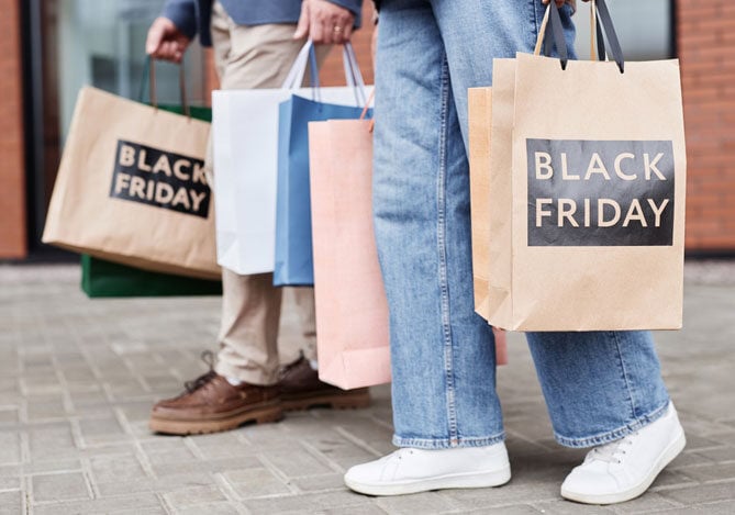 Mercado Pago: duas pessoas segurando sacolas de compras que fizeram ao pedir empréstimo para comprar na Black Friday. 