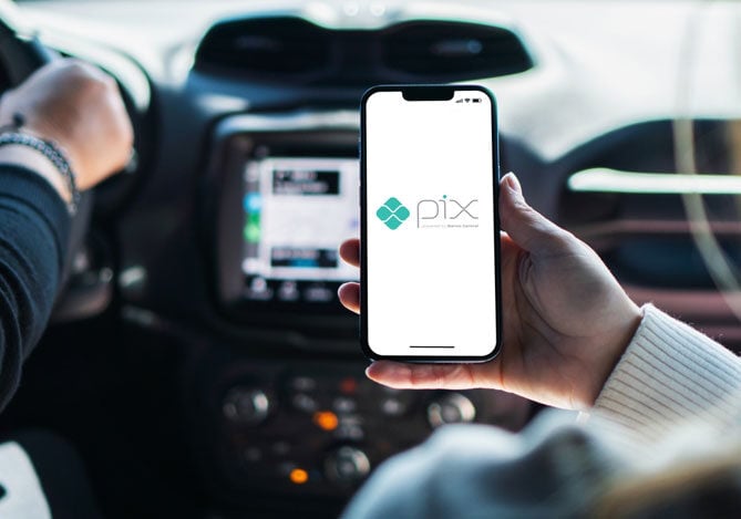 Mercado Pago: Mão de pessoa segurando um celular com o símbolo do Pix aberto, simbolizando a necessidade de se proteger de um Pix falso. A pessoa se encontra em um carro, com alguém dirigindo, simbolizando corrida de aplicativo. 