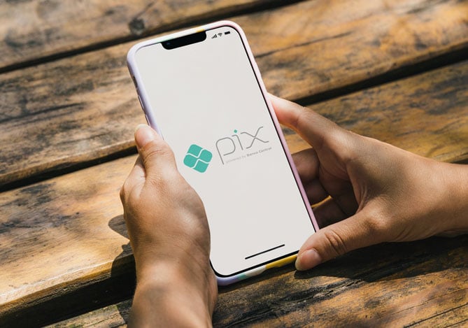 Mãos de uma pessoa segurando um smartphone com a tela aberta no símbolo do Pix citando as facilidades do Pix no crédito do Mercado Pago