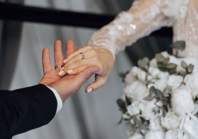 Mercado Pago: imagem das mãos de um casal durante a cerimônia de casamento que foi realizada após o casal ter planejado tudo, graças a uma boa organização e um bom conhecimento sobre quanto custa casar. 