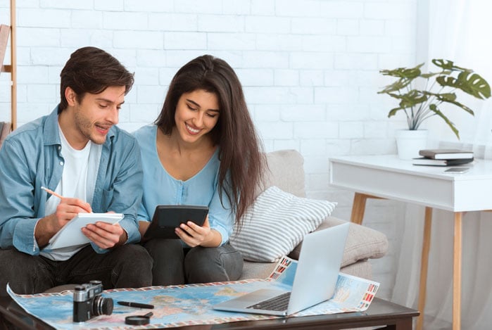 Mercado Pago: homem e mulher sentados no sofá, fazendo contas em papel e calculadora para criar sua reserva financeira 