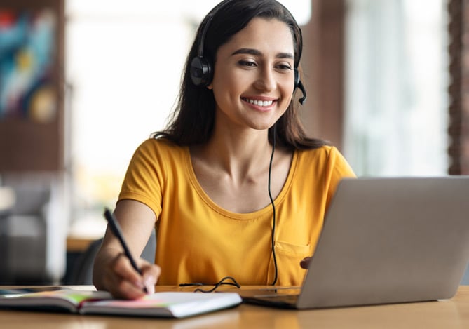 Menina com computador aberto para estudar para o Enem sem gastar muito e com a ajuda do Mercado Pago. 