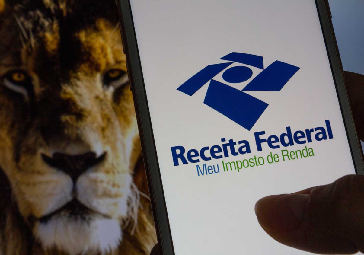 Um leão de fundo e um celular com a tela do aplicativo da Receita Federal