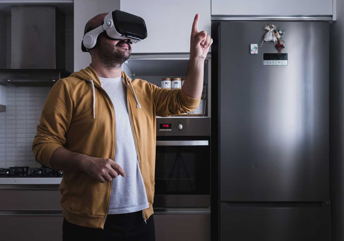 Um homem com óculos de realidade aumentada em uma cozinha apontado para o teto. 