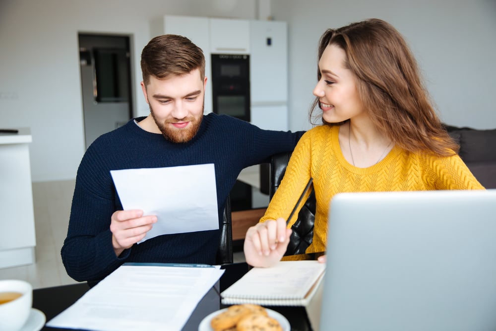 Casal jovem e feliz fazendo as contas para economizar e investir seu dinheiro.