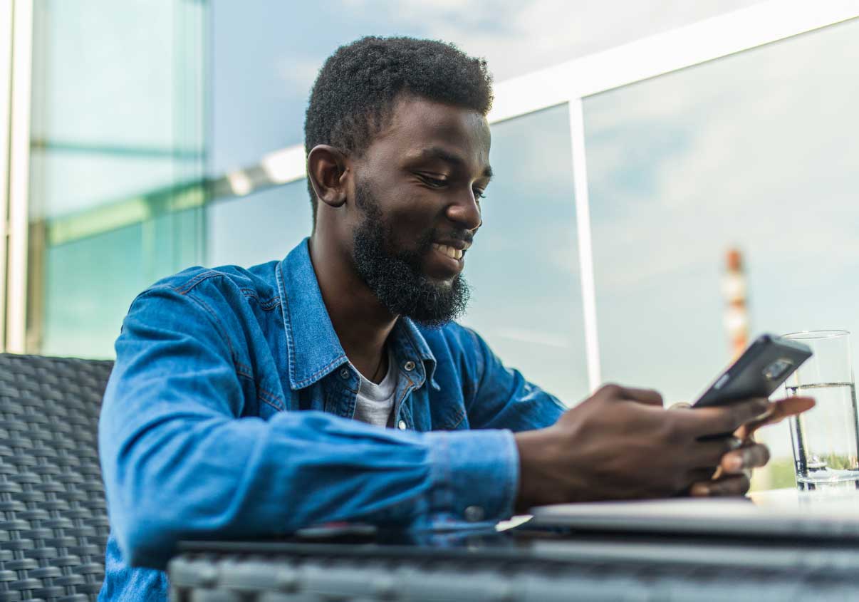 Um homem sorridente olhando para a tela de um celular